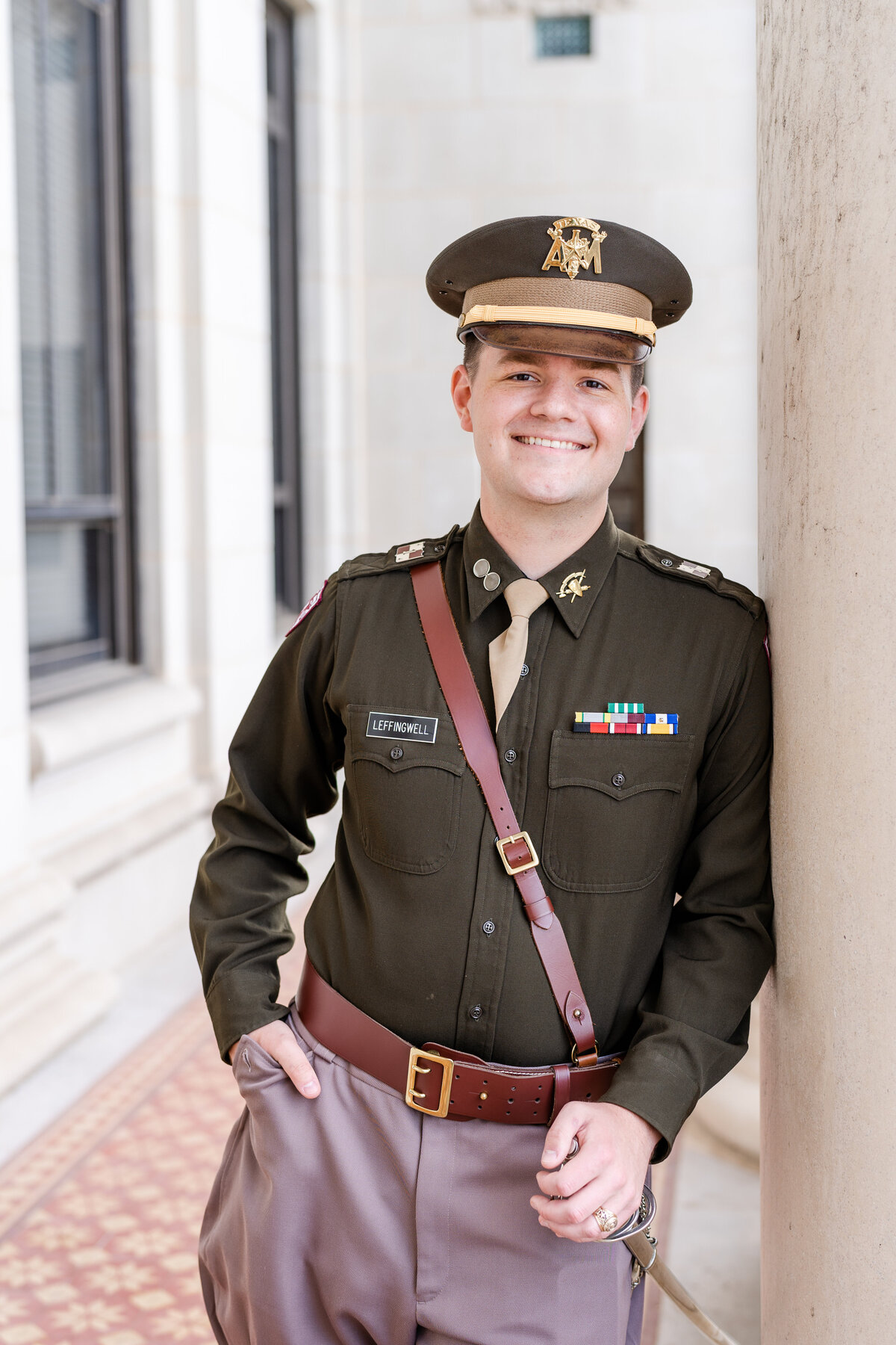 Texas A&M senior guy in CORPS uniform smiling and leaning against column at Administration Building
