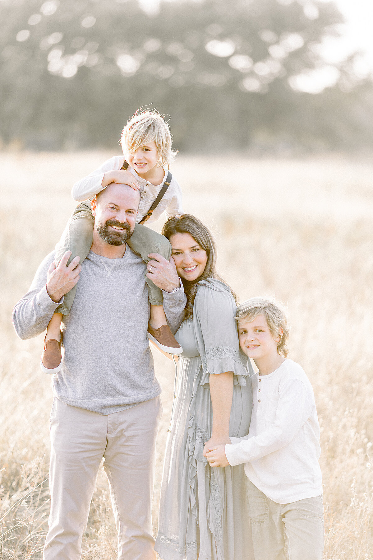A beautiful Frisco Tx Family posing in the middle of a field for family photos.