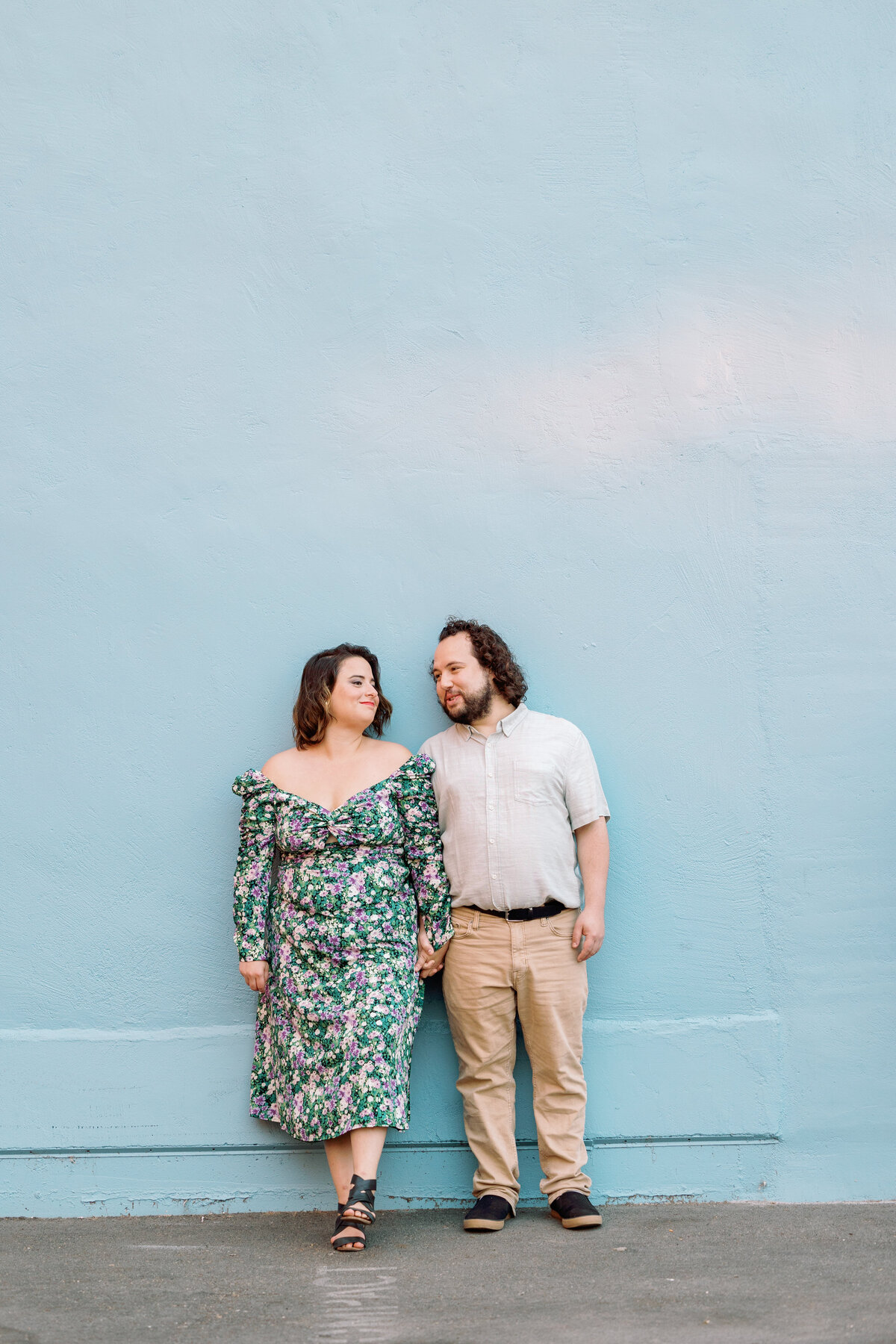 A couple holding hands and standing against a wall