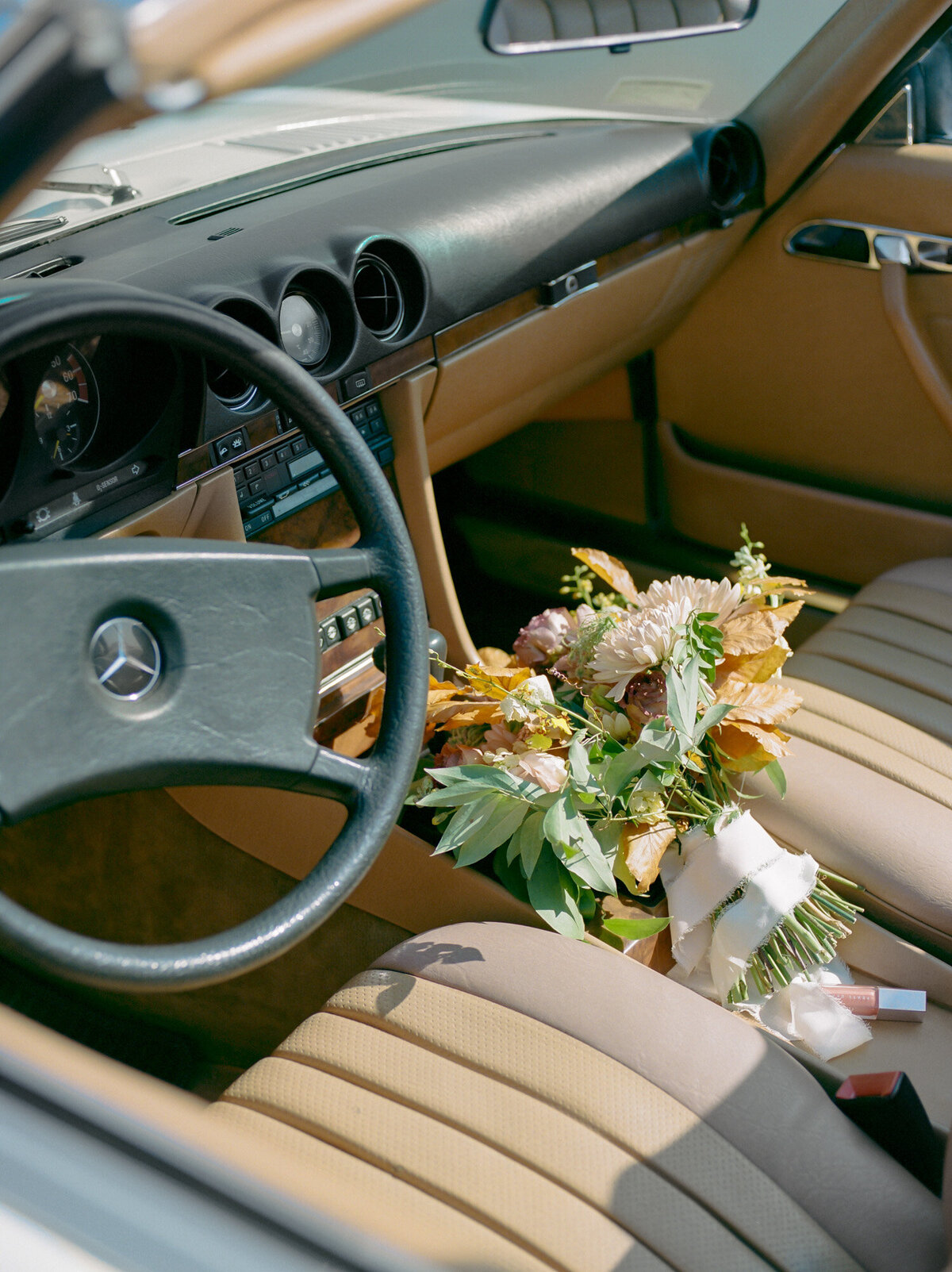 bridal bouquet & lip gloss rest in a vintage mercedes convertible in Detroit, Michigan