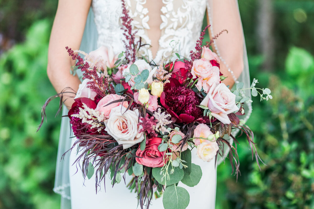 Bride holding bouquet with pink and burgundy flowers