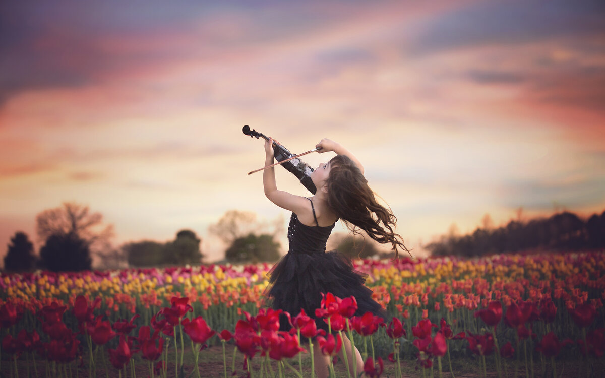 Young girl dancing in field of tulips wiht a violin.