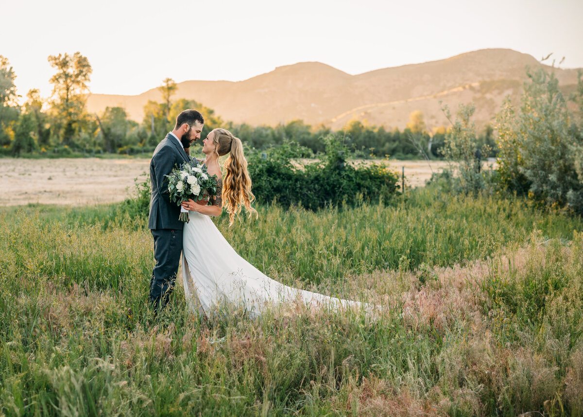 couple in the sunset colors surrounding the mountains at Jackson Hole Wyoming with beautiful florals and dipping to kiss