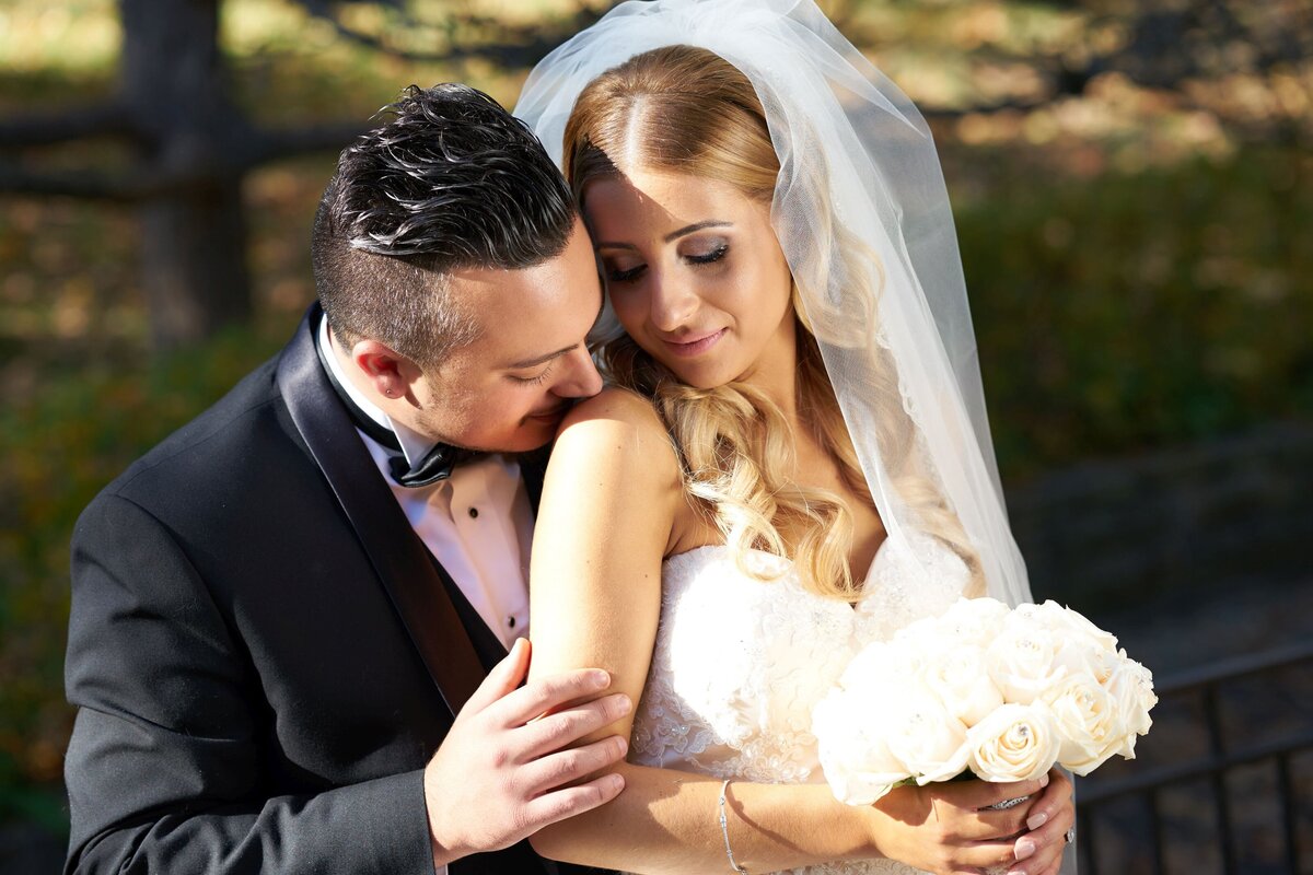 An intimate moment where the groom gently kisses the bride's shoulder. The image captures the tender affection and romantic connection between the couple, showcasing their deep bond and love.