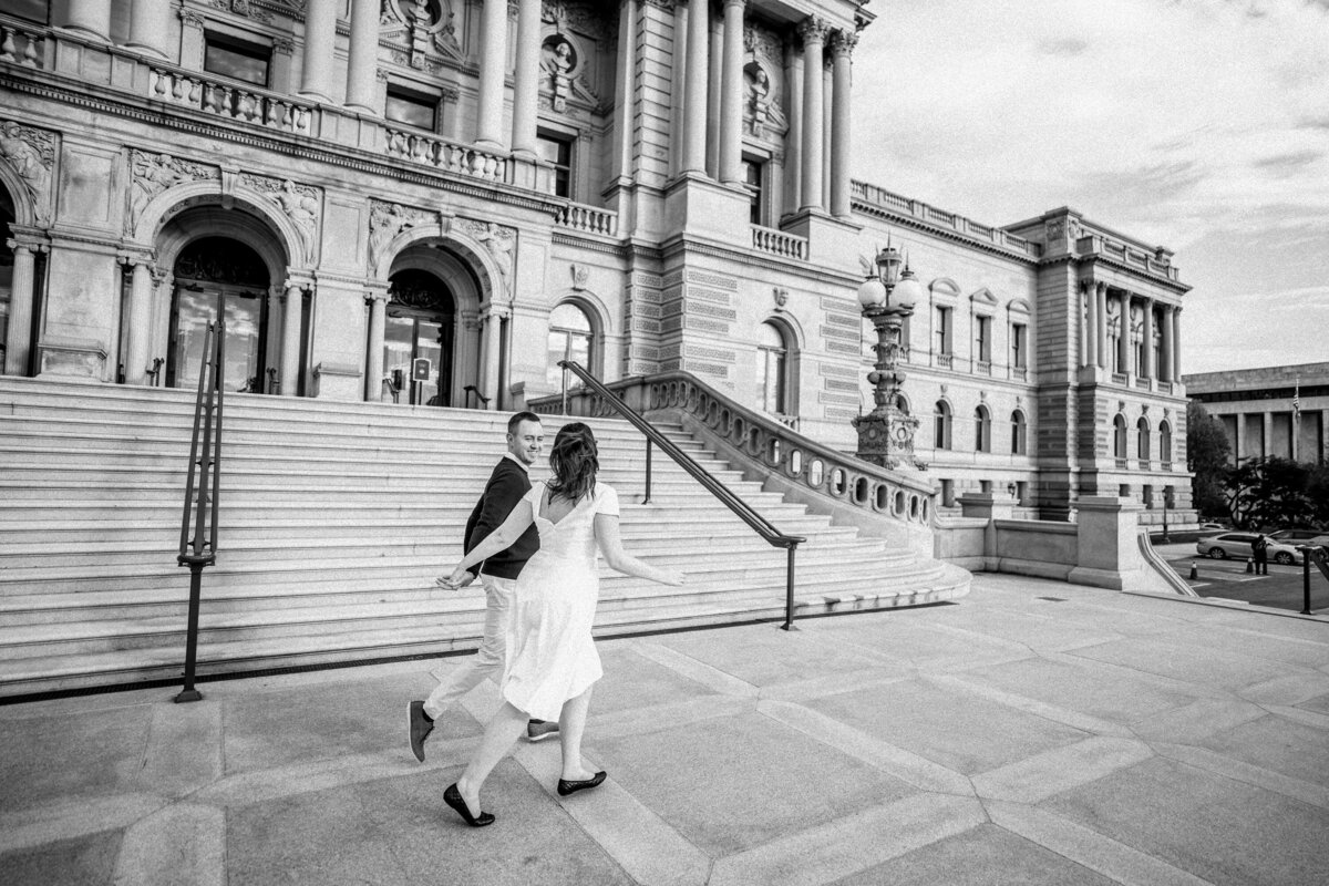 couple run together in front of library of congress in Washington D.C. at engagement session