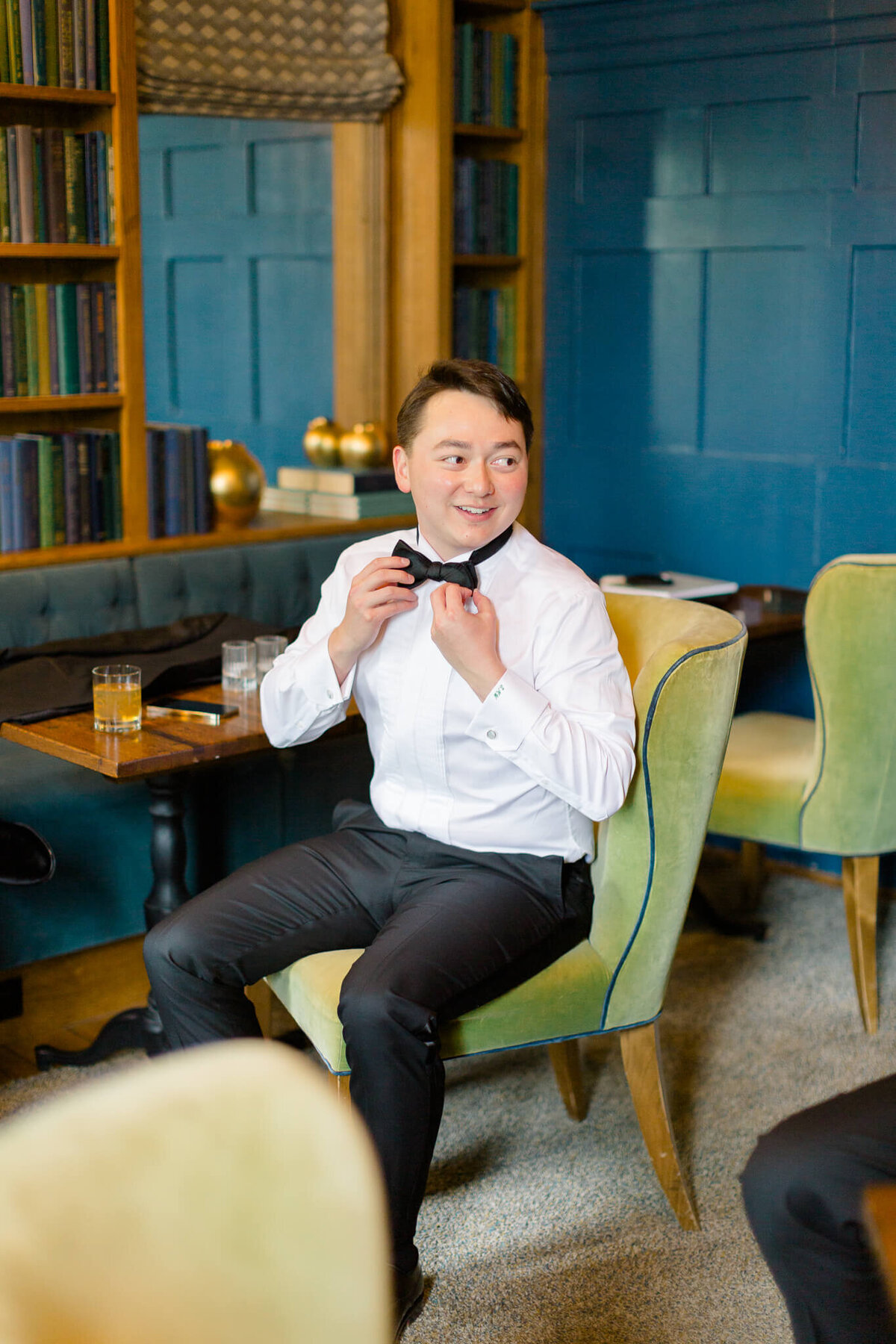 Groom getting dressed in the library at The Clifton.