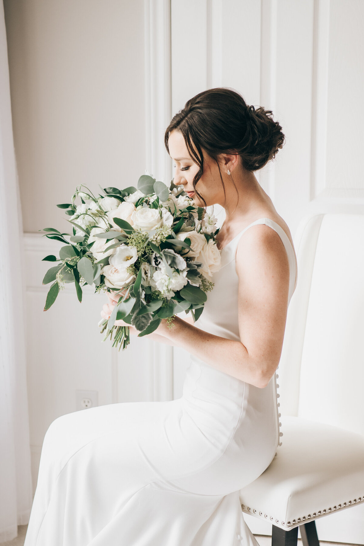 An elegant bride sitting with her gorgeous white wedding bouquet