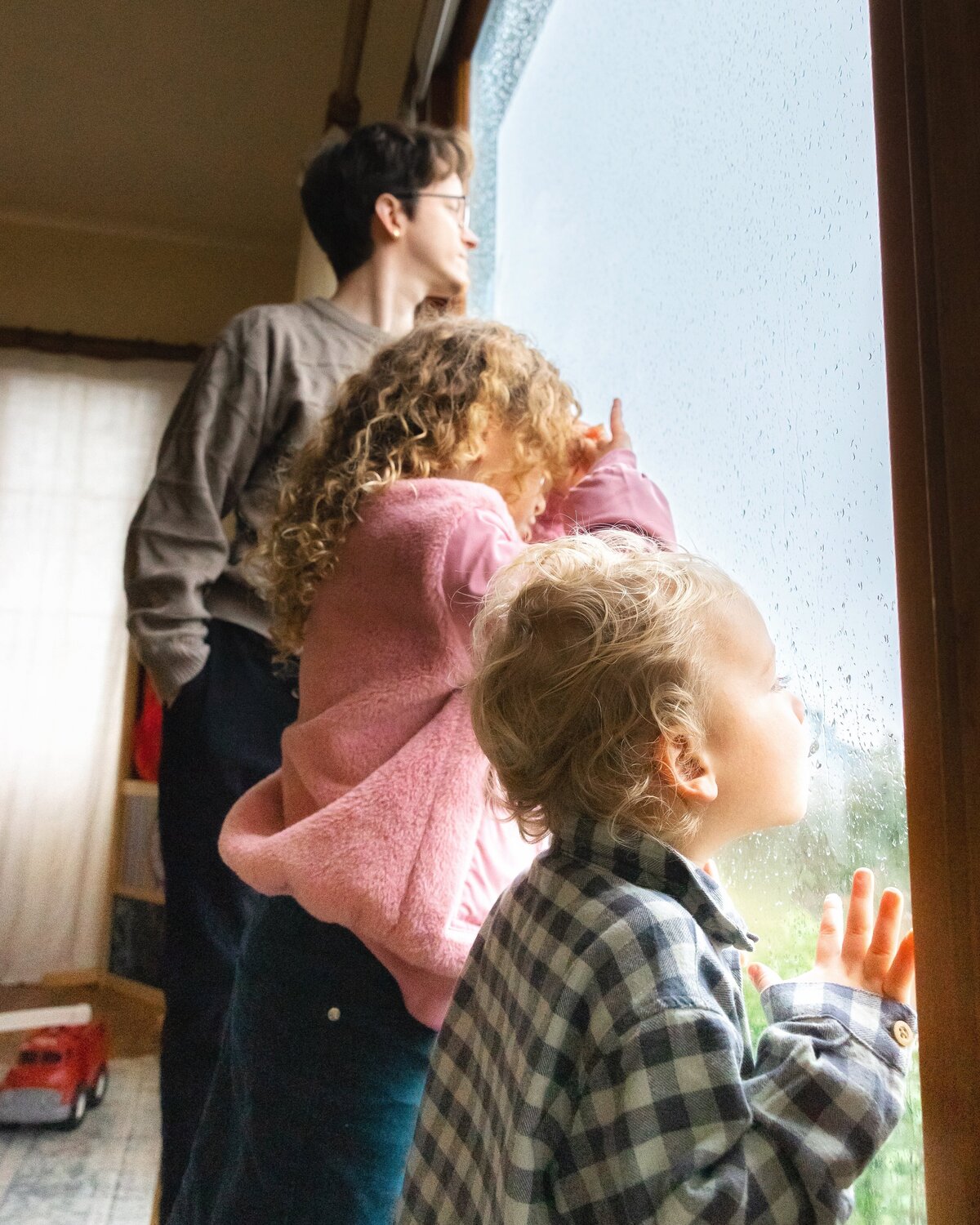 Three siblings look at the window of their house