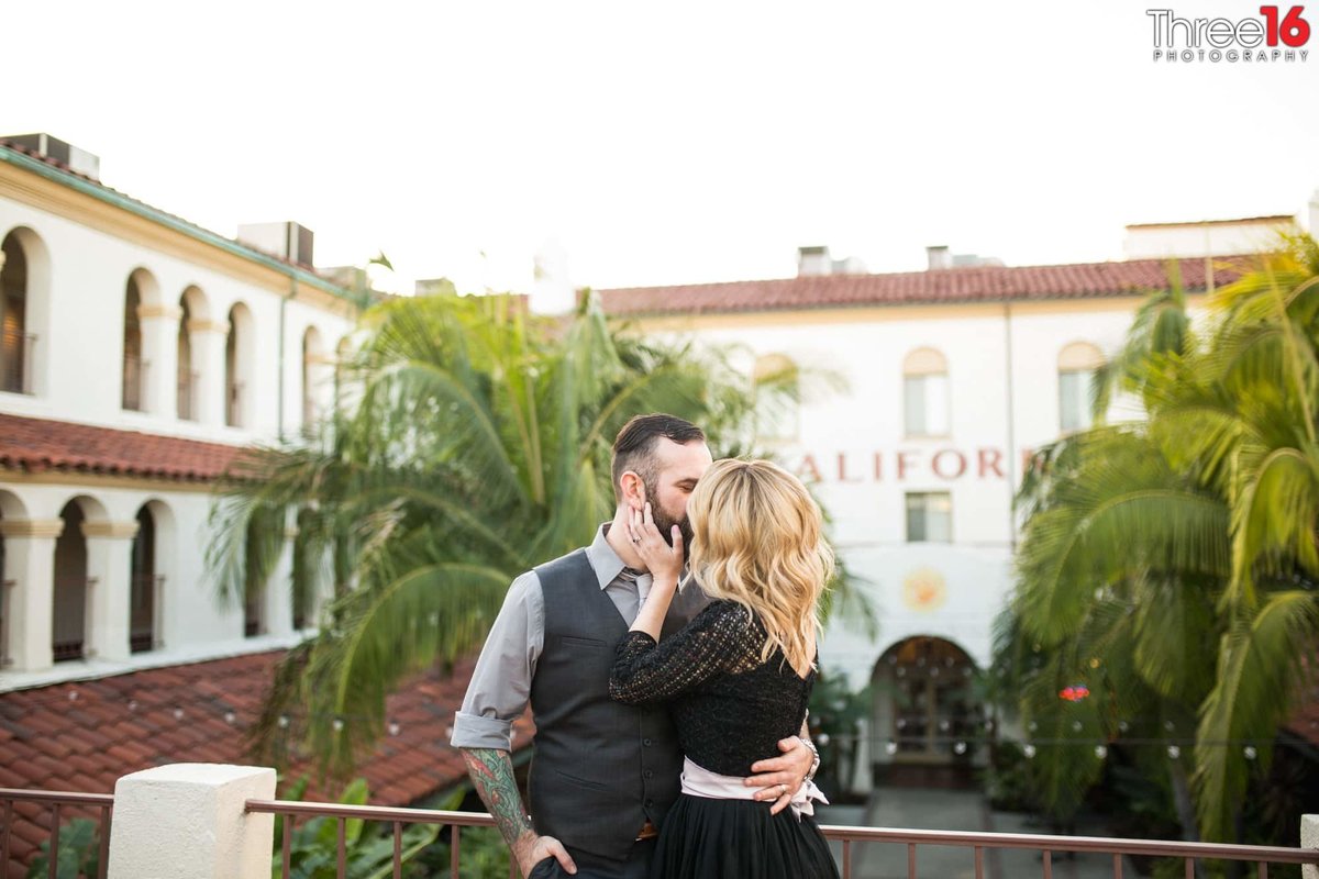 Engaged couple share a tender kiss overlooking the Villa Del Sol courtyard