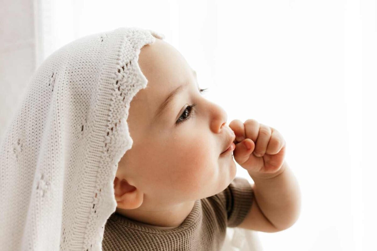 Ruua Hamdan Photography (UK): A baby is looking up and touching its mouth.