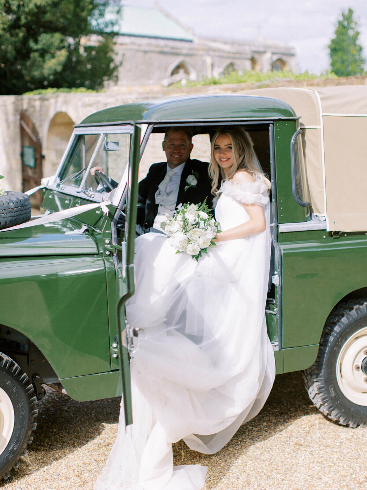 bride and groom sitting in the land rover vintage wedding car