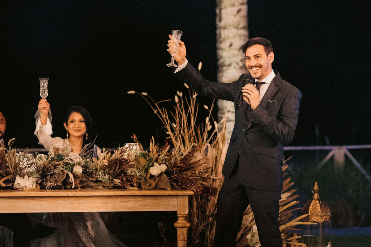 The bride and a guest are holding wine glasses up in the air in Khayangan Estate, Bali, Indonesia. Image by Jenny Fu Studio