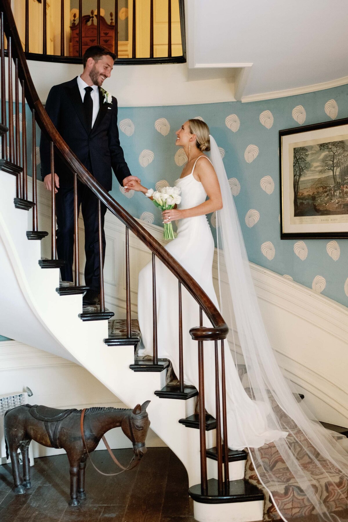 brick house shelburne museum vermont wedding couple goes upstaircase with blue wallpaper