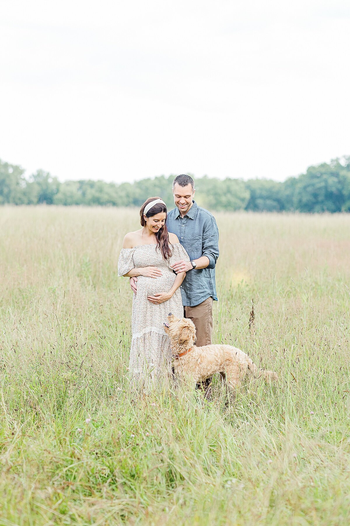 couple and dog in field during maternity photo session at heard farm in Wayland Massachusetts with Sara Sniderman Photography
