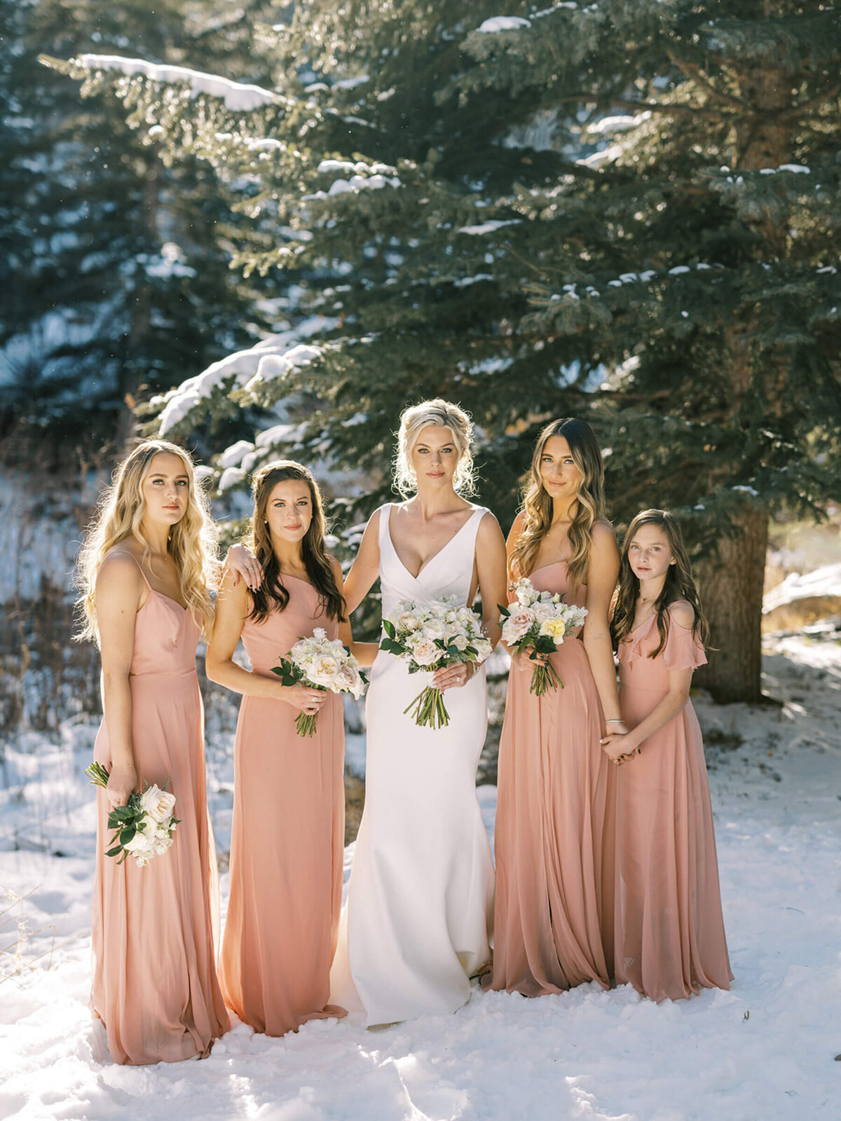 Bride and bridal party in blush dresses at a winter mountain wedding in Vail, Colorado