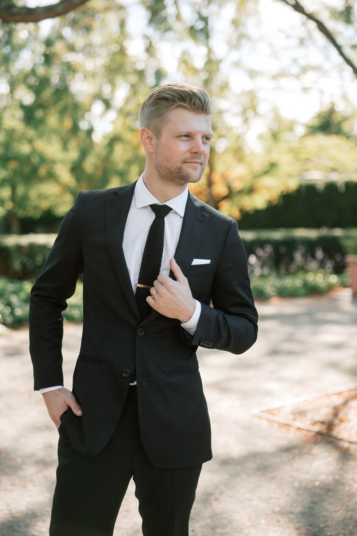 Groom adjusts his suit jacket during outdoor wedding in Dayton, Ohio, captured by Philadelphia wedding photographer.