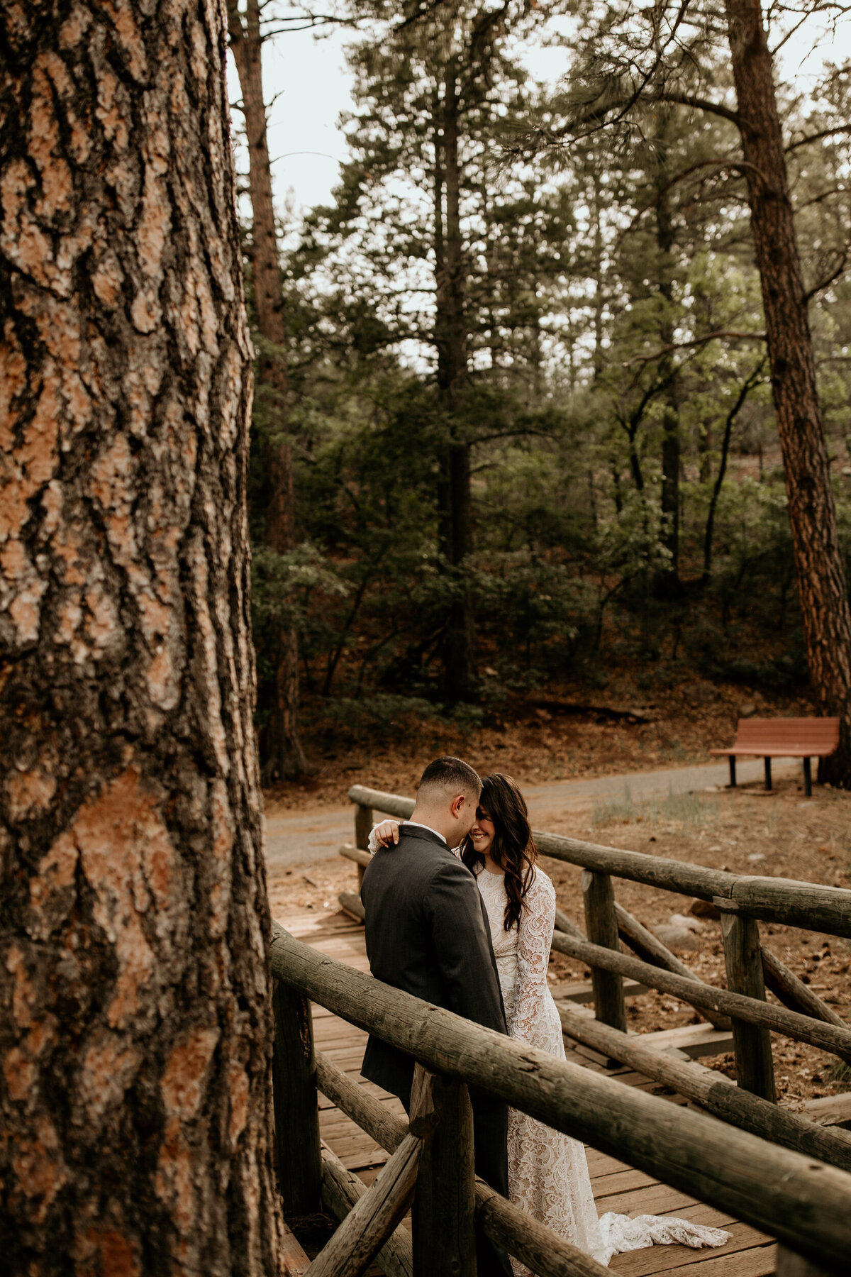 bride and groom standing on a bridge together in the forest in New Mexico