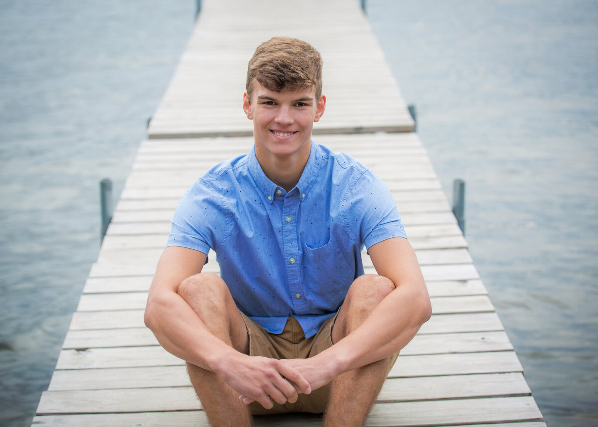 Boy senior pictures bright, vibrant style on Keuka Lake in Penn Yan, NY on dock dressed in blue