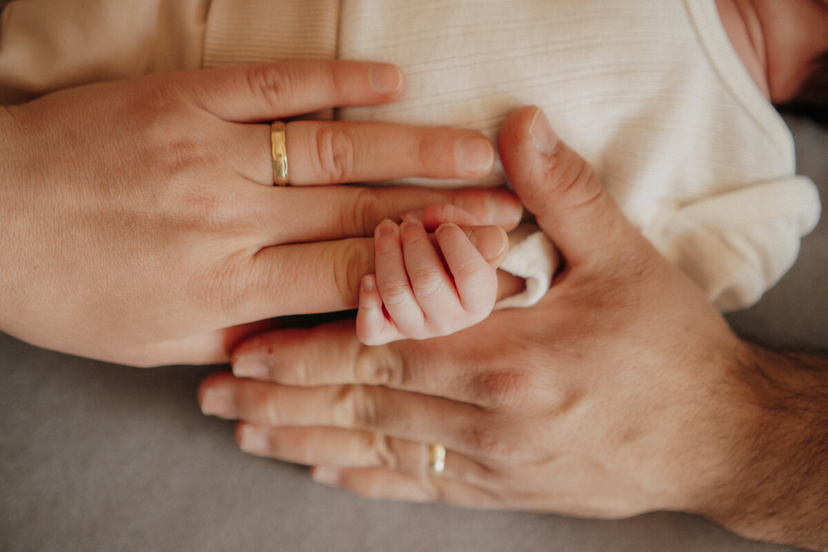 Eltern umfassen das kleine Händchen des Babys
