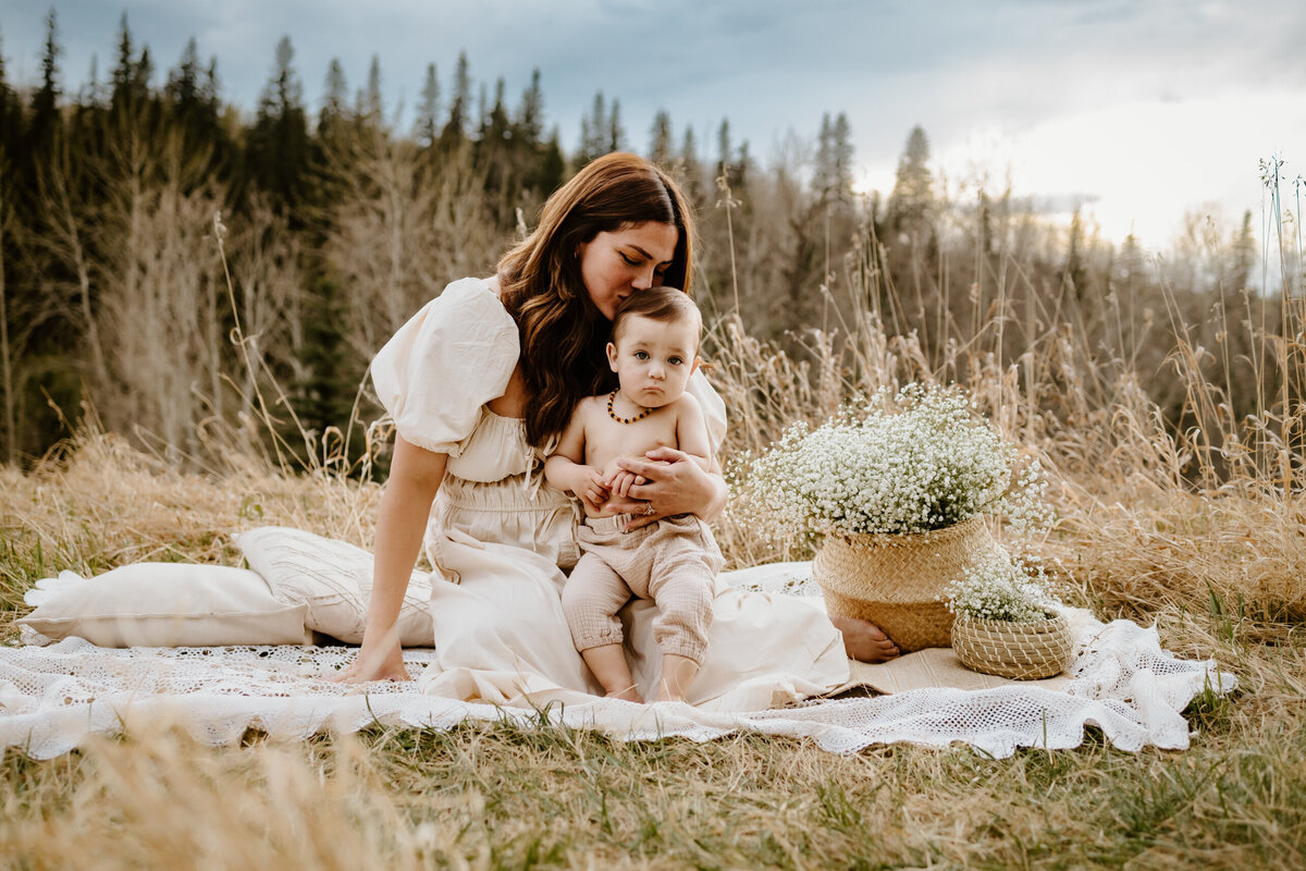 Mom kissing toddler son on a blanket