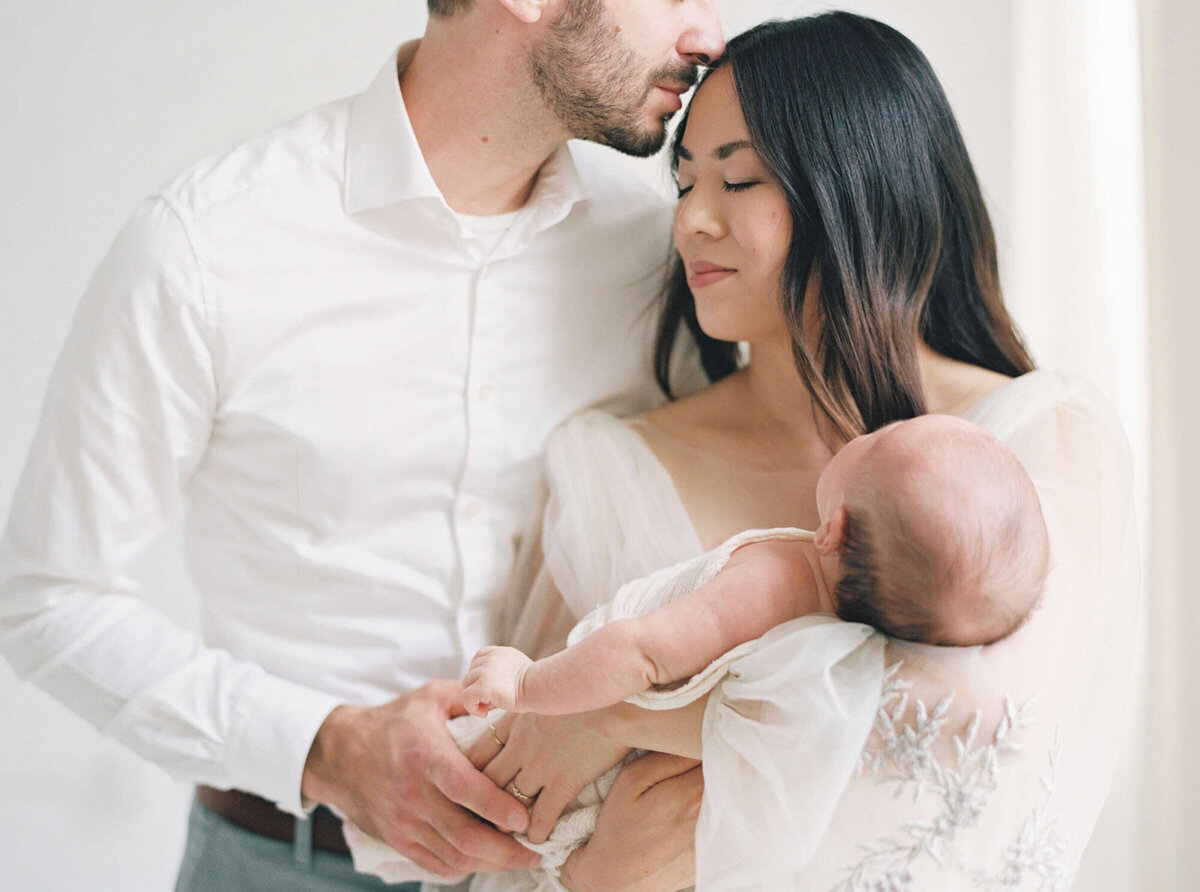Parents cuddling their newborn during an in-home San Francisco Bay Area newborn photographer session.