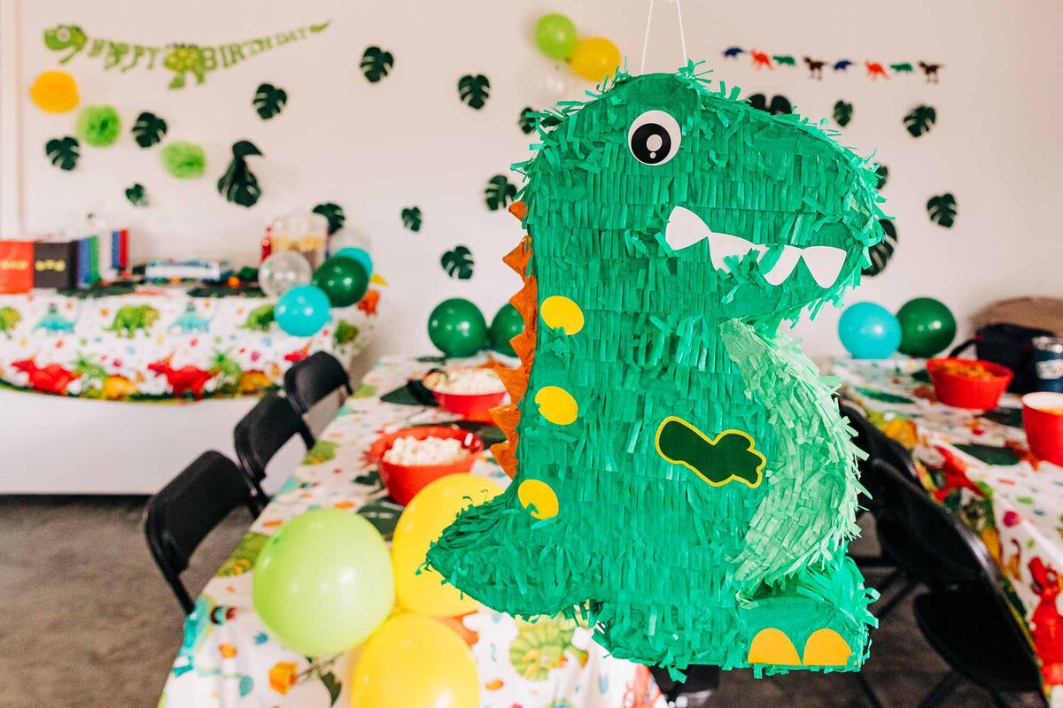 Hanging green dinosaur pinata at 6 year old birthday party