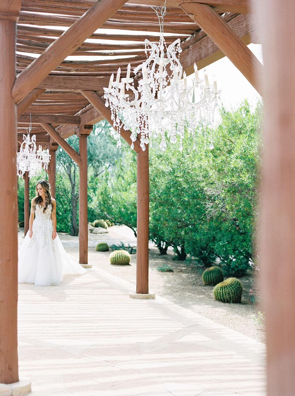 A stunning bride walks under twinkling chandeliers in a beautifully rustic yet elegant wedding venue.