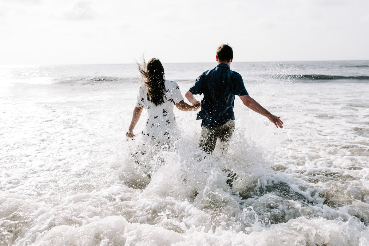man and woman running through ocean