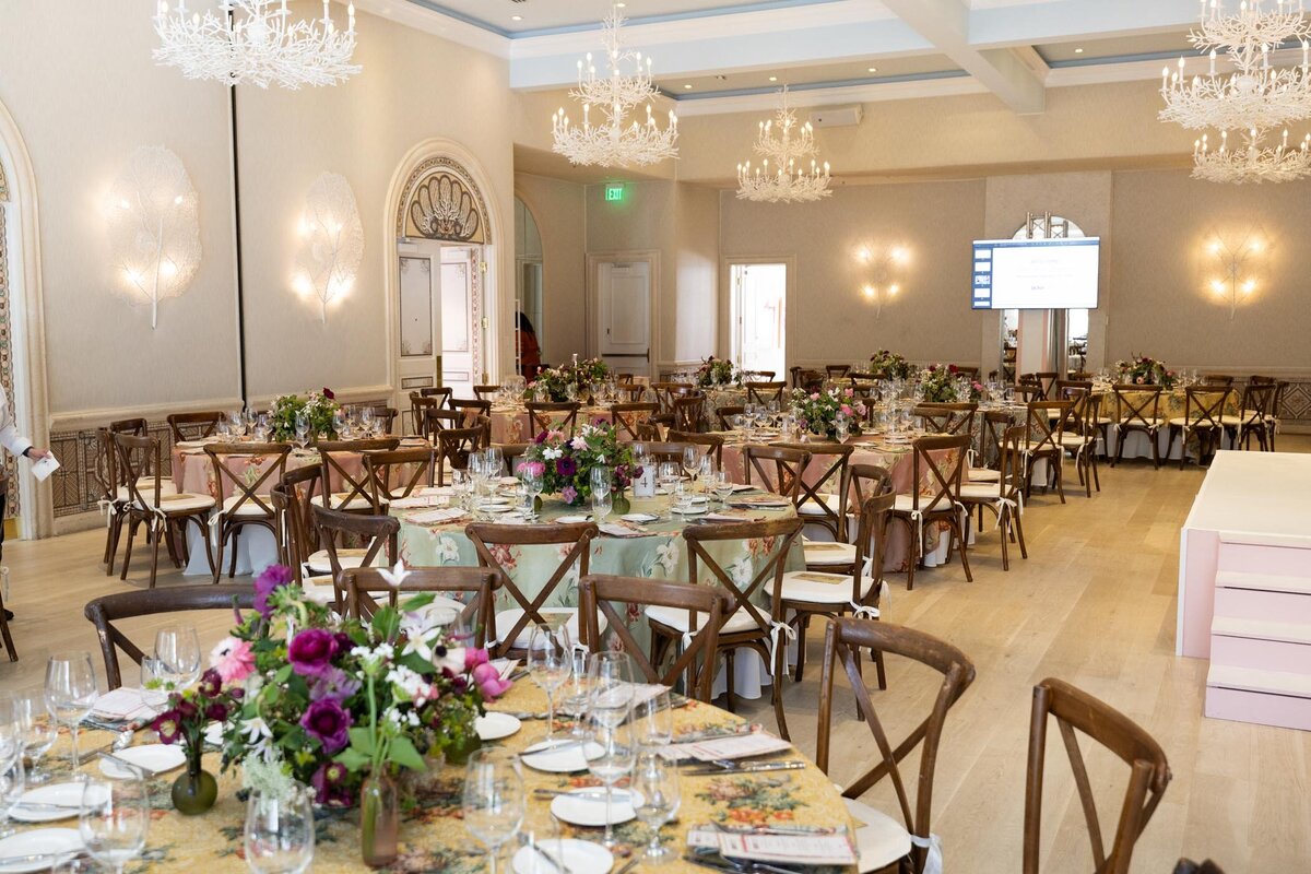 Round banquet tables adorned with floral centerpieces and place settings inside the dining ballroom.
