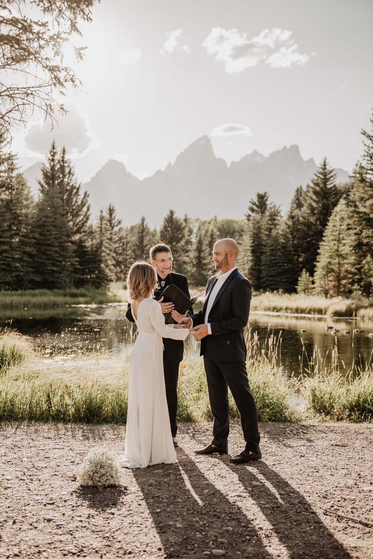 wyoming elopement with Bride and groom holding hands next to a lake at the Tetons for their ceremony photographed by jackson wyoming photographer