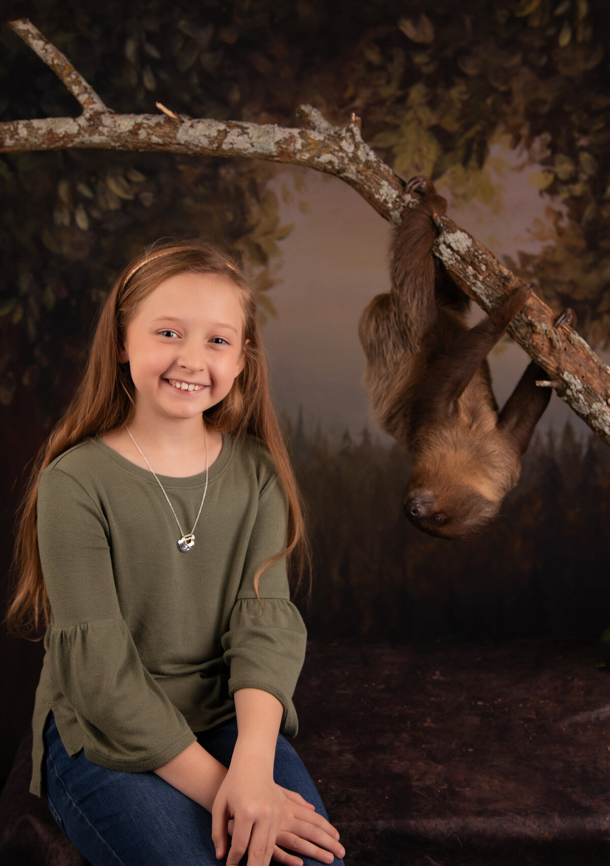 girl smiling with a sloth in studio portrait