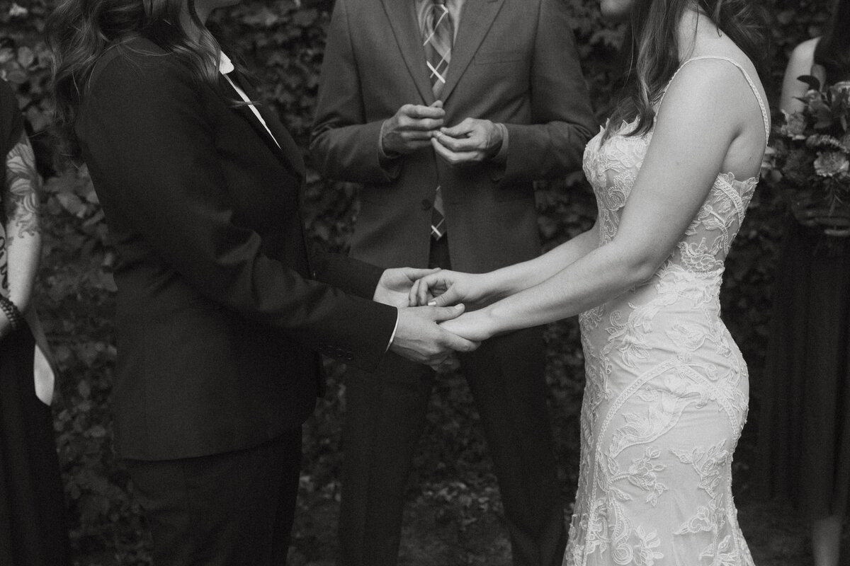 A close up of two people holding hands during their wedding ceremony 