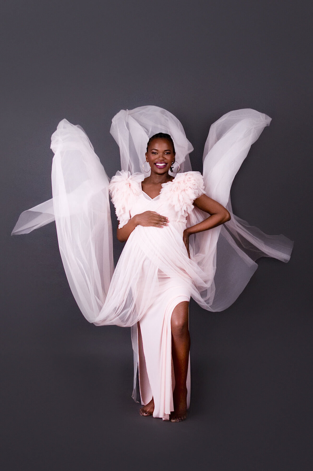 Romantic couple pose beside flowing pink gown.