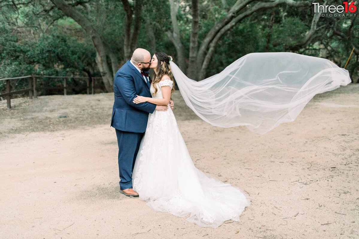 Bride and Groom share an after ceremony kiss as the Bride's veil flails in the wind