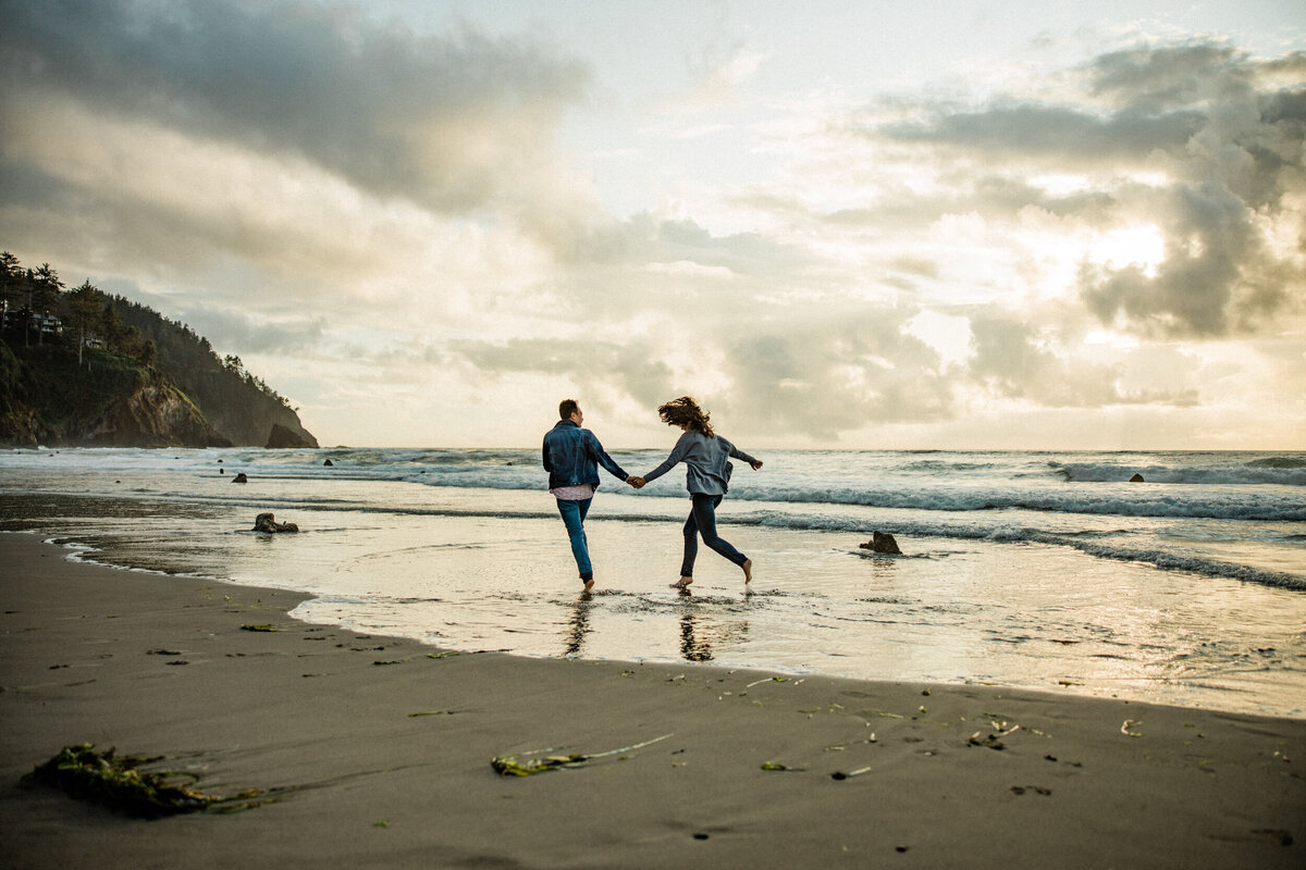 husband and wife run along beach for romantic engagement and couples photos