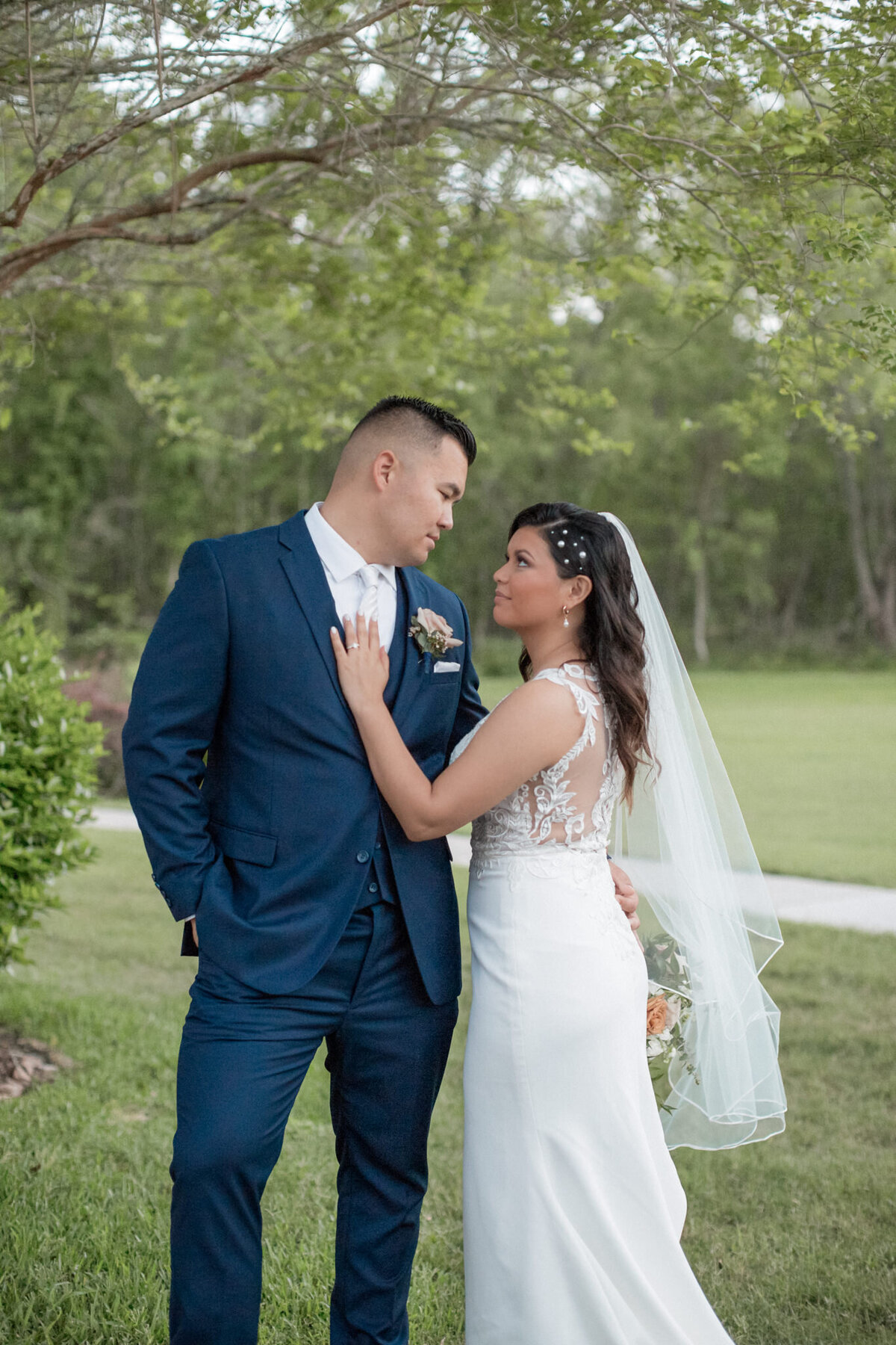 The just married couple gaze into each others eyes as the bride displays her new ring on her husbands chest