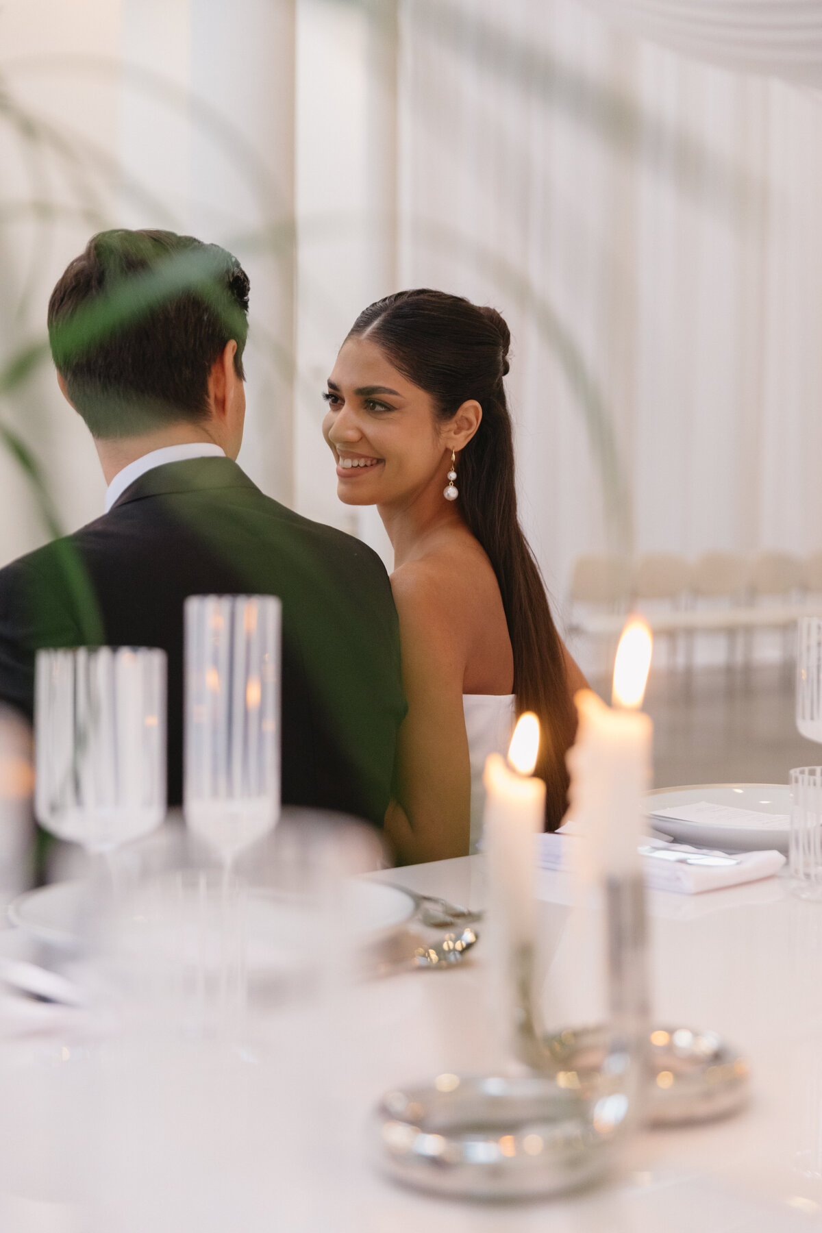 Bride and groom sharing a quiet moment in a minimalist white wedding space with soft candlelight.