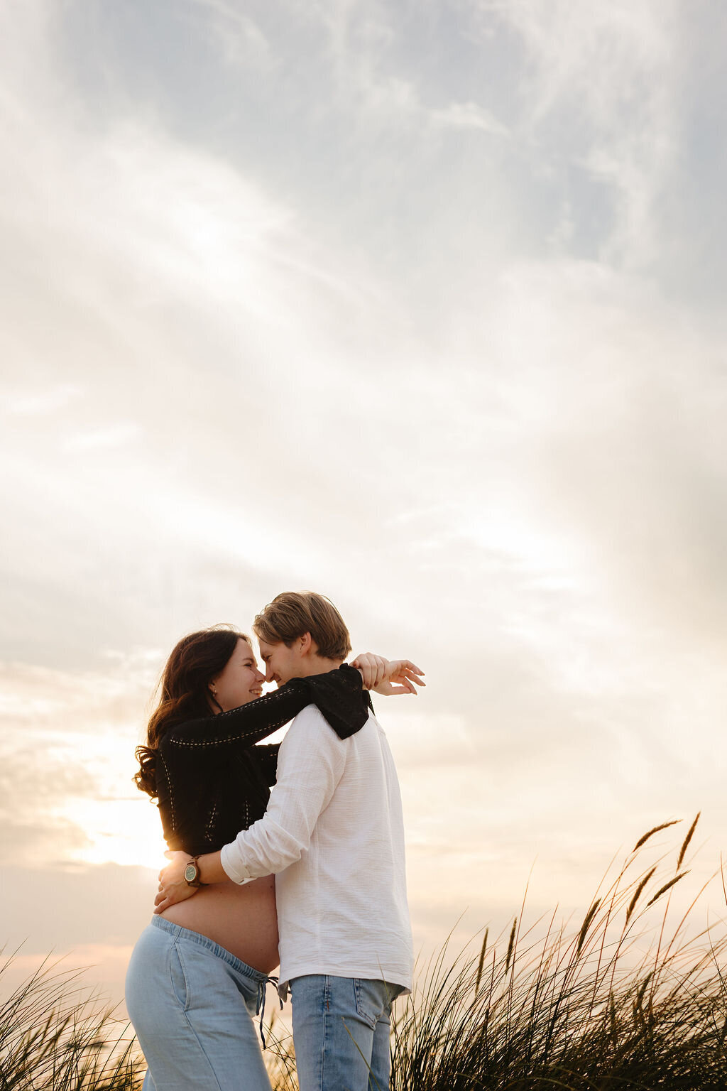 Koppel omhelst elkaar tijdens zwangerschapsshoot