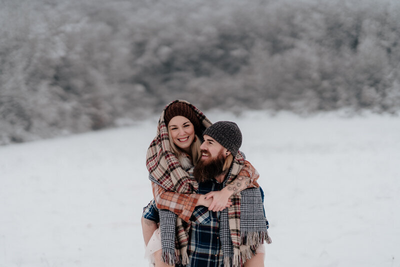 Portrait rapproché d’un couple en Haute-Savoie sous la neige, blottis l’un contre l’autre dans une étreinte chaleureuse et intime.
