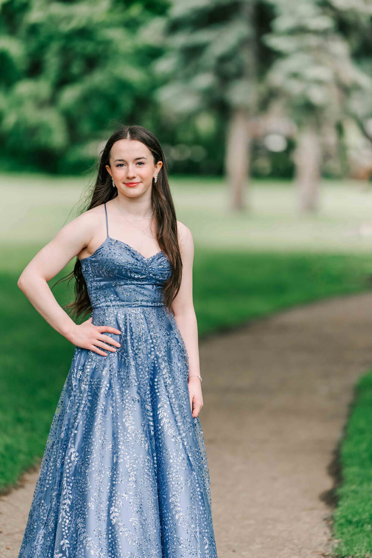 Girl in a purple dress standing on a pathway. 