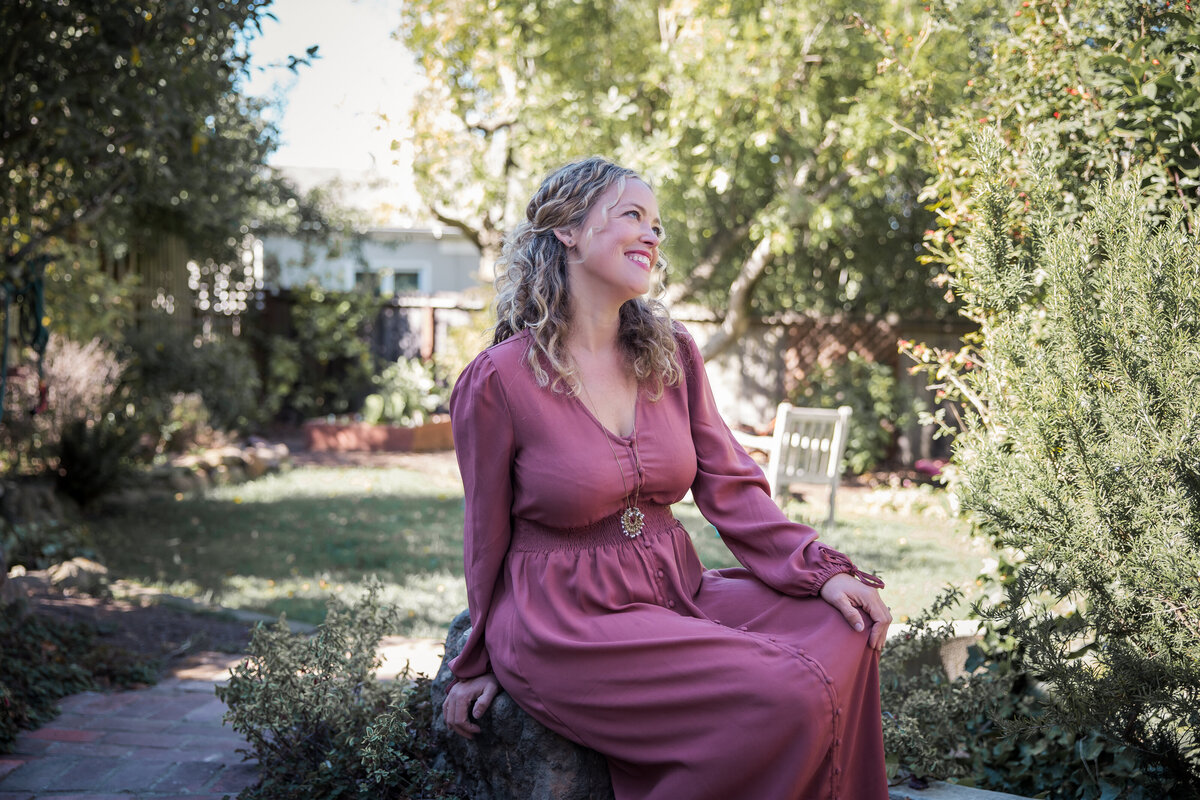 Woman sits in a garden and smiles
