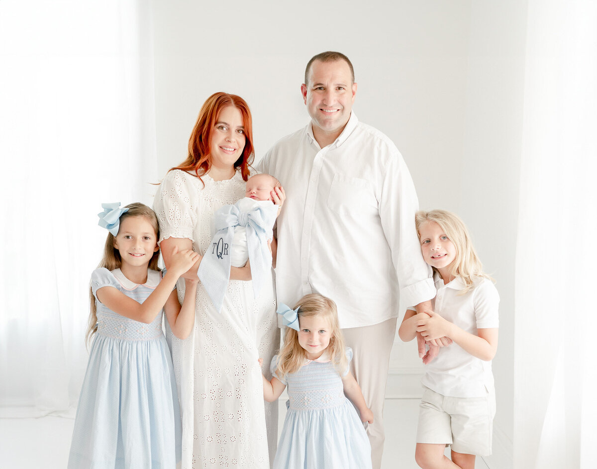 Family with 4 children pose In Kristie Lloyd’s Nashville newborn photographer studio