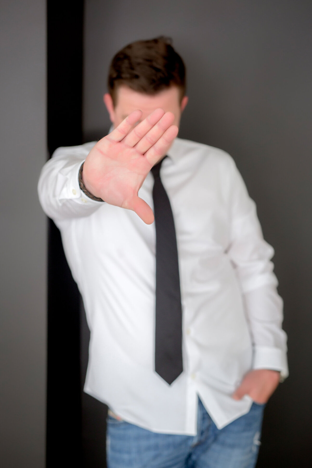 Male entrepreneur wearing a white button-down & black tie with his hand up to the camera, blocking his face to the South Shore MA branding photographer