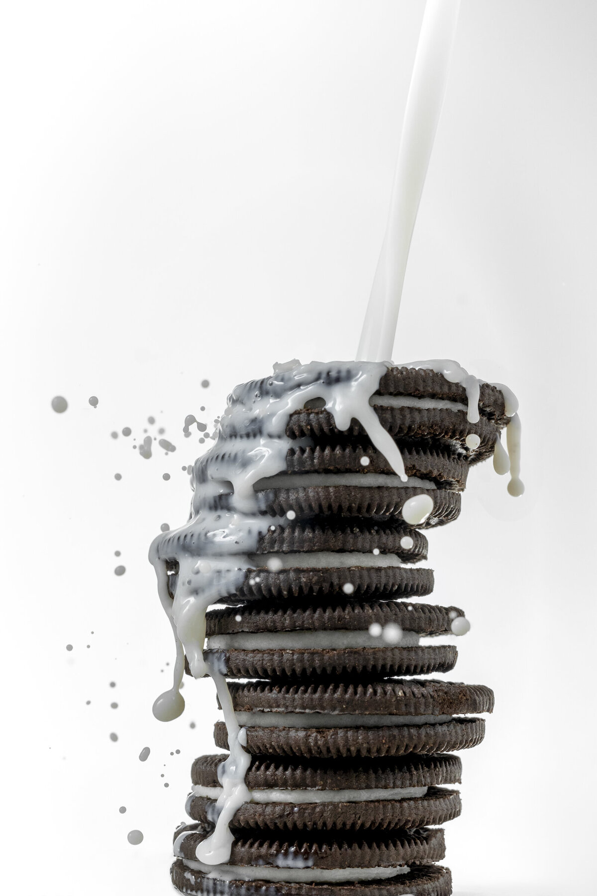 Oreos and milk splash photography on white background.