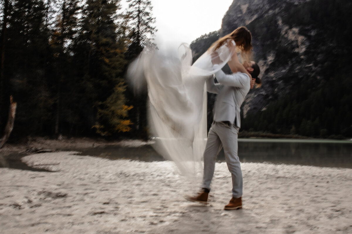 Elopement wedding couple posing on a cliffside with dramatic mountain views