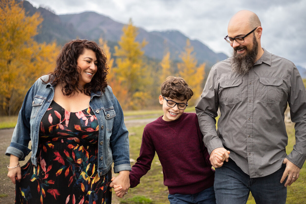 Family of three walking while holding hands  in the Columbia River Gorge during Fall season. Photo by Portland Oregon family photographer.
