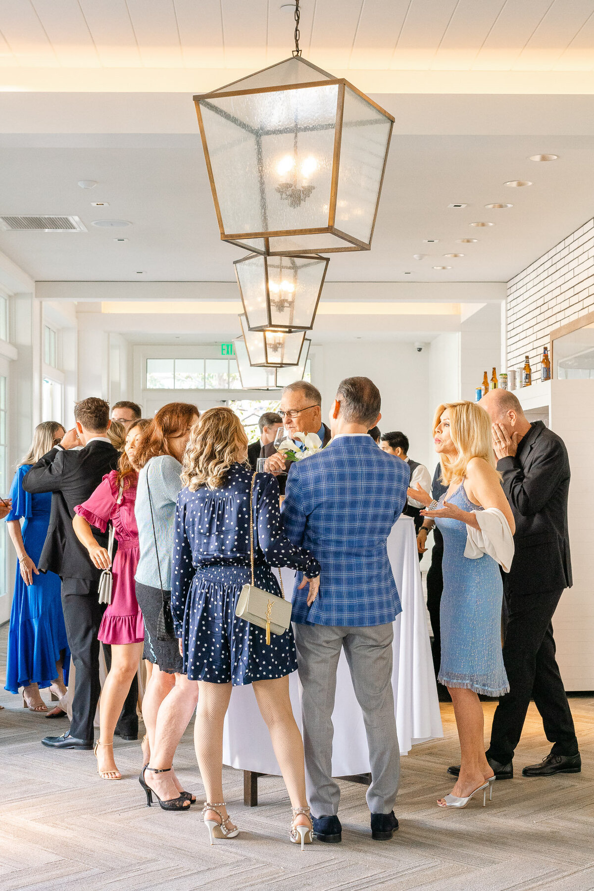 Wedding guests gather and mingle during the cocktail hour at a luxury wedding reception inside Lido House, enjoying drinks and lively conversations