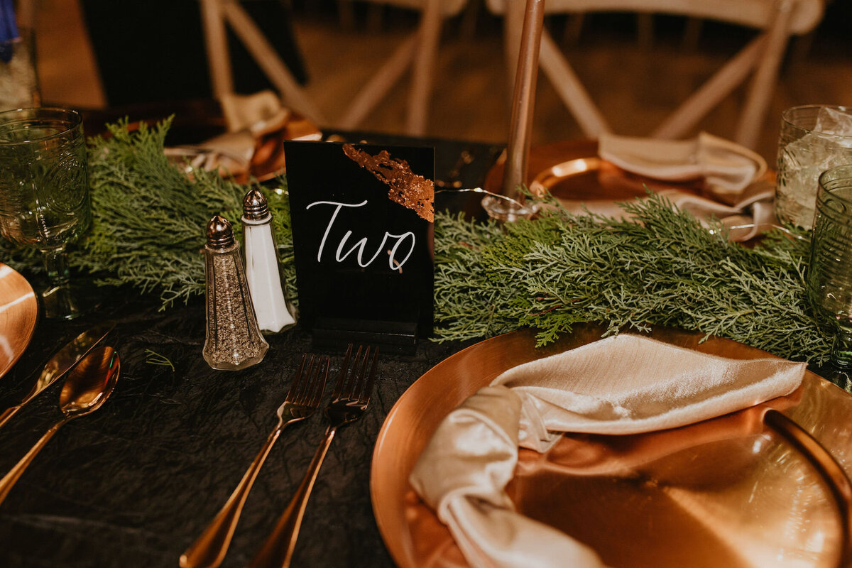 Custom black and white table numbers with rose gold decor for a winter wedding