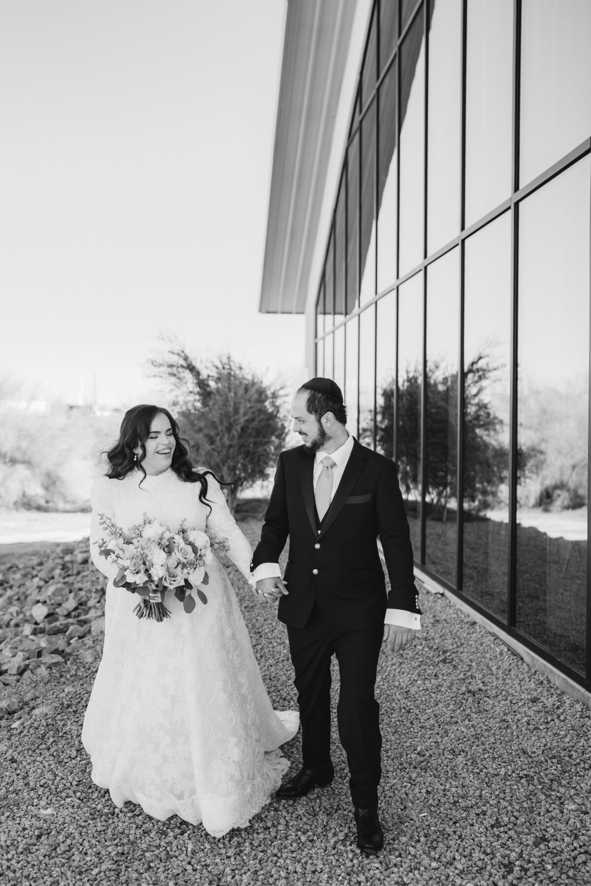 Bride and groom walking next to building