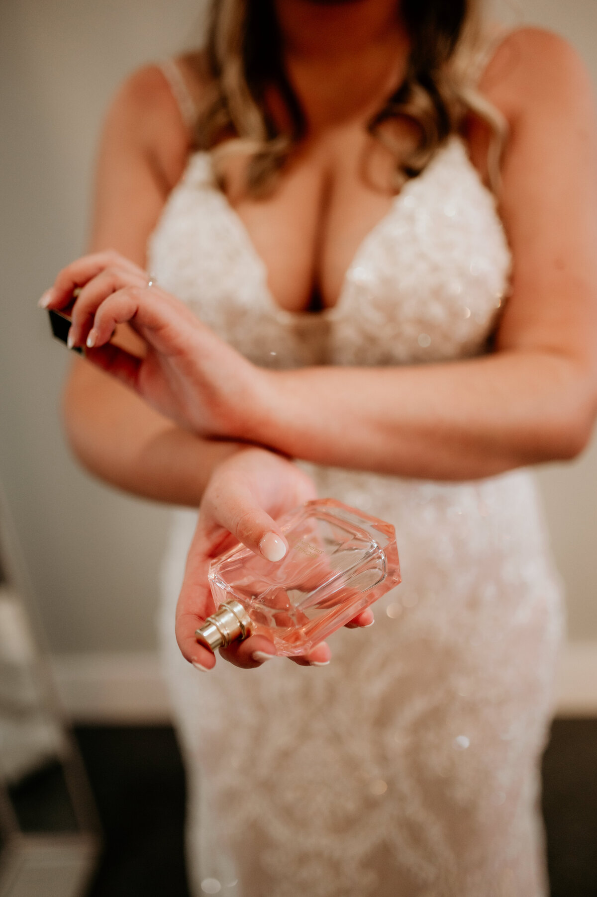bride rubbing her wrists together as she puts on her wedding perfume in her little rock ar bridal suite